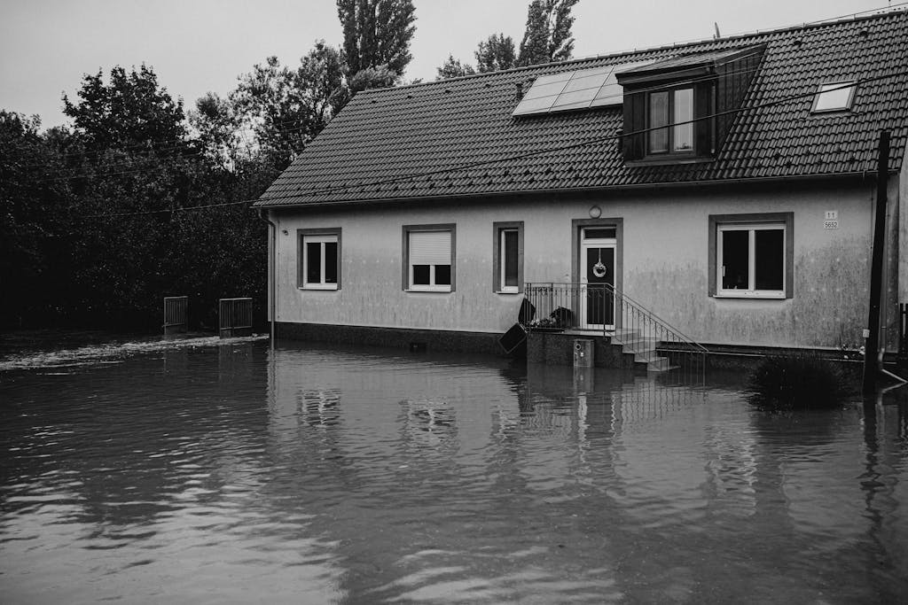 A monochrome image of a suburban house affected by floodwaters.