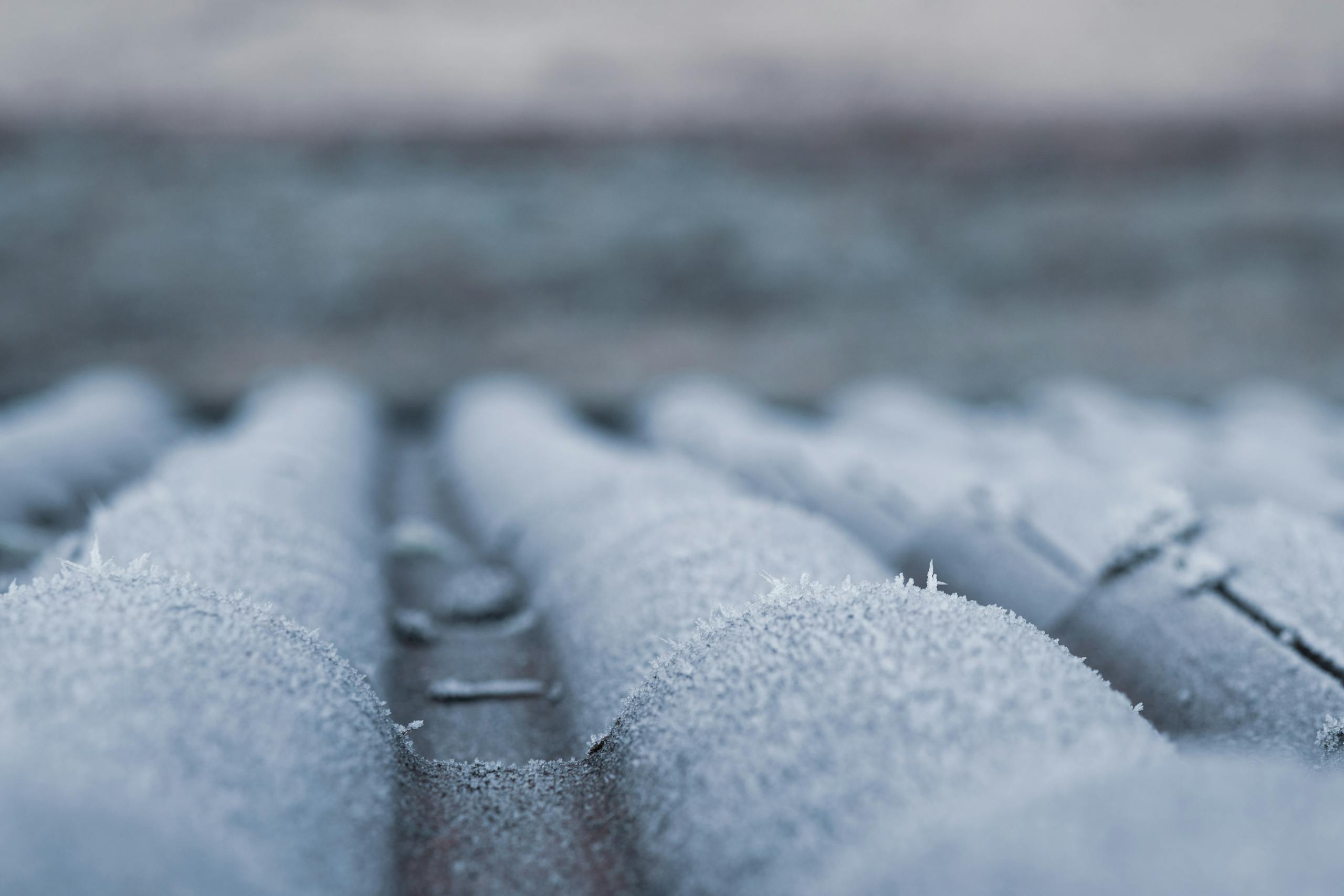 Close-up of frosty roof shingles showcasing winter's icy grip and cold atmosphere.